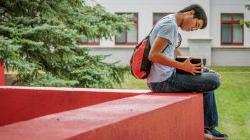 student reading a book on the quad in summer